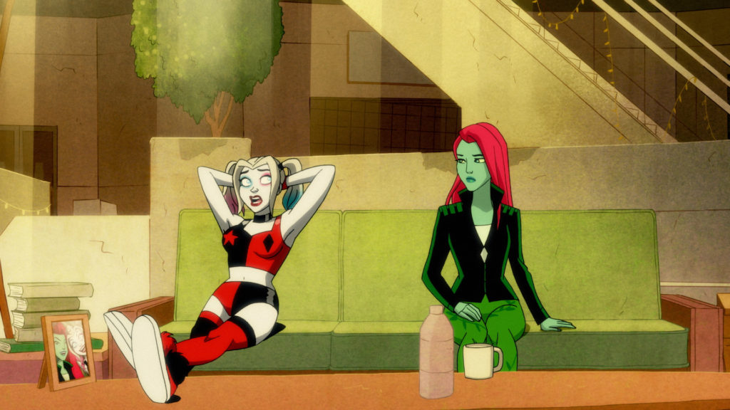 Harley Quinn and Poison Ivy sit on a couch as they discuss the Kiss.