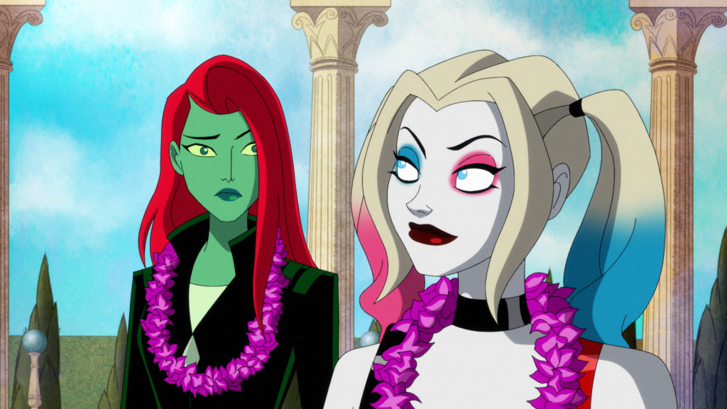 Harley Quinn looks at Poison Ivy in Themyscira. They are both wearing leis.