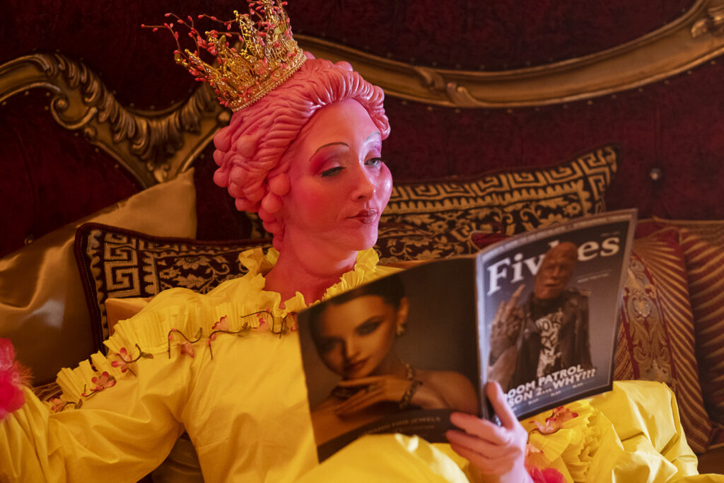 Jhemma Ziegler as the Scant Queen reading an magazine. The cover features Cliff and asks "Season 2 . . . What?"