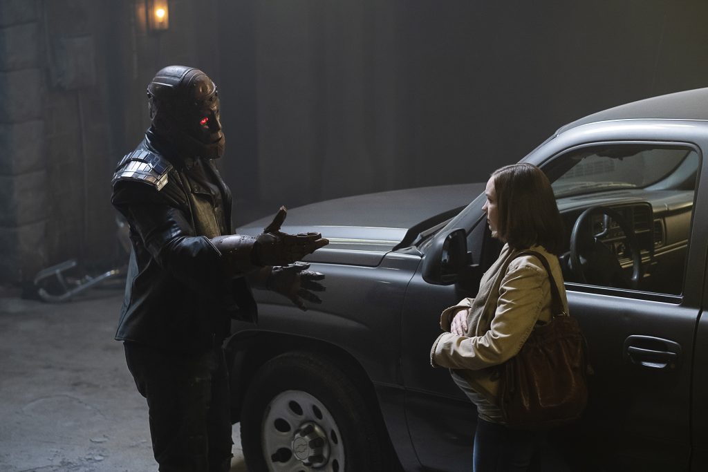 Left to Right: Cliff talking to his pregnant daughter, Clara, in front of a car in a garage.