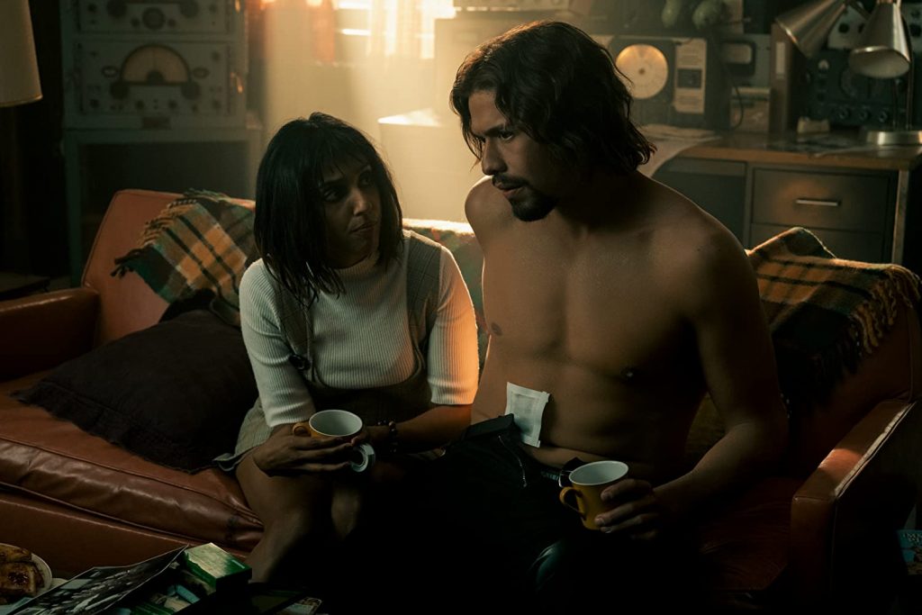 Lily with a cup in hand and Diego, shirtless, also with a cup in hand. Both listening to Five's plan.