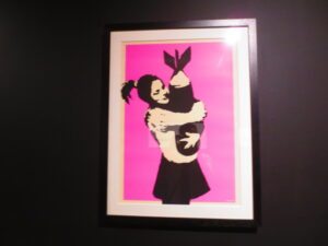 Bomb Love (Bomb Hugger) by Banksy. Silkscreen print of a girl hugging a bomb like a teddy bear