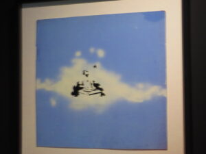 Cloud DJ by Banksy. Stencil of a spray-painted DJ in the clouds with a saw behind him on blue cloth