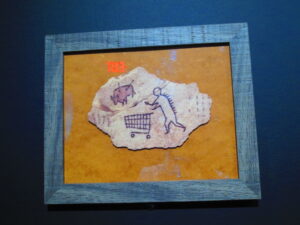 Peckham Trolley, Postcard by Banksy. A primitive cave drawing of a man using a shopping cart and passing by a buffalo shot through with arrows