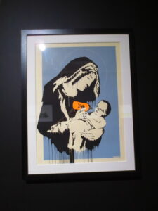 Virgin Mary (Toxic Mary) by Banksy. Silkscreen print of the Virgin Mary giving little baby Jesus a milk bottle with a toxic sign