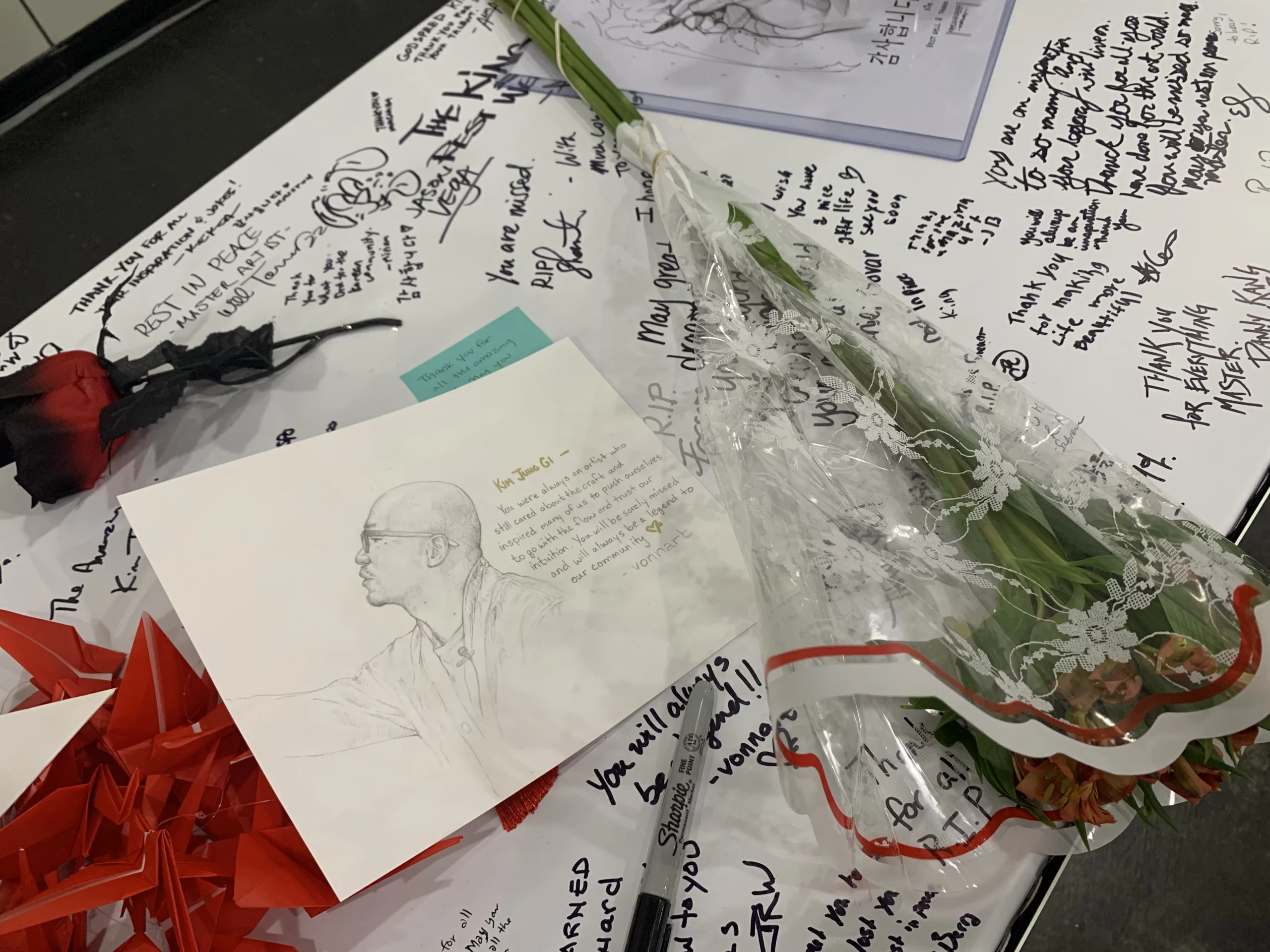 flowers and notes left on Kim Jung Gi's Artist Alley table
