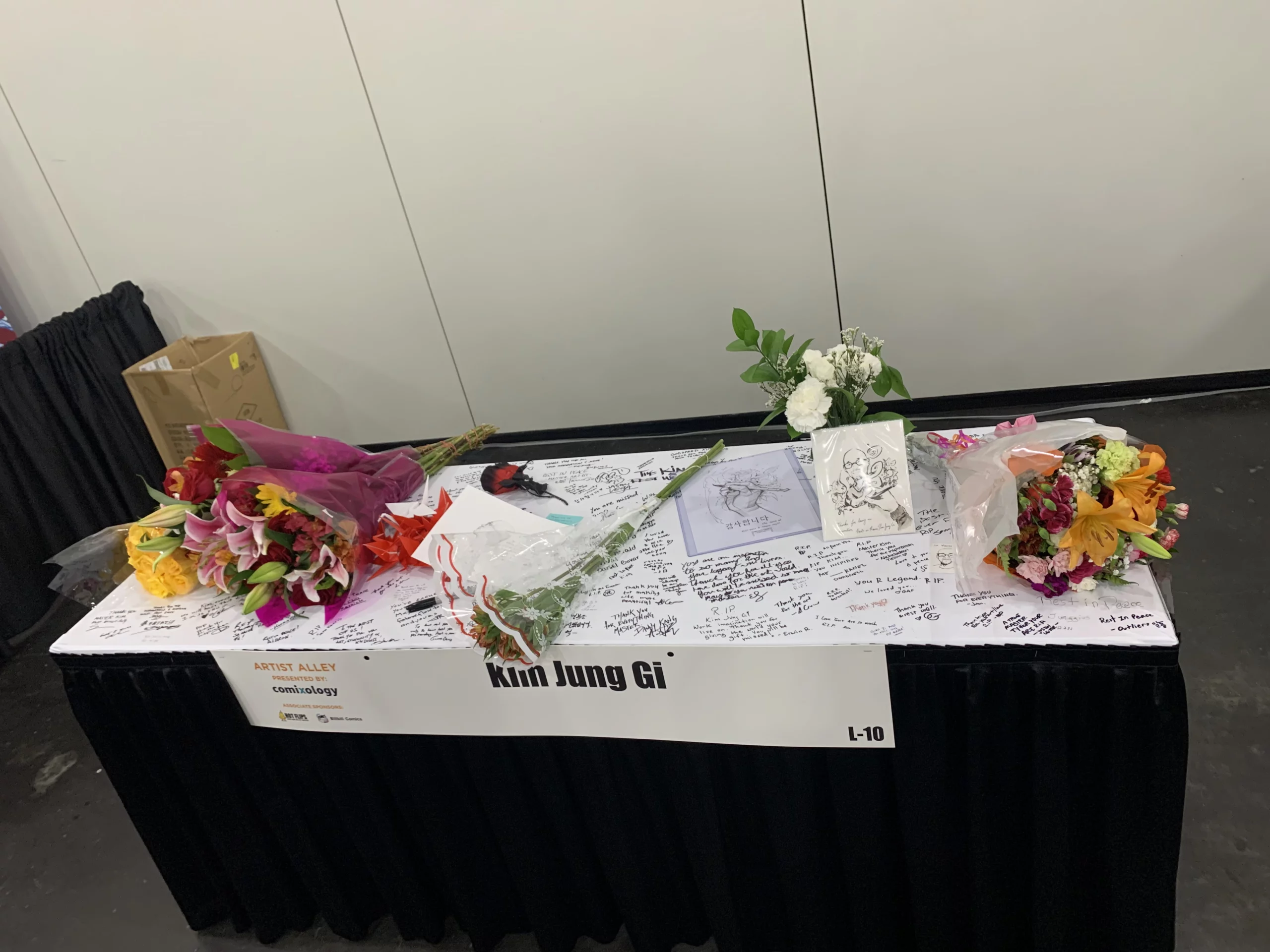 Flowers and notes left on Kim Jung Gi's Artist Alley table at New York Comic Con