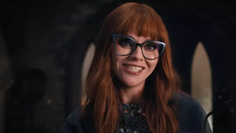 Christina Ricci with red bangs, hair drooping over the shoulder, and glasses, as Laurel Gates in Netflix's Wednesday.