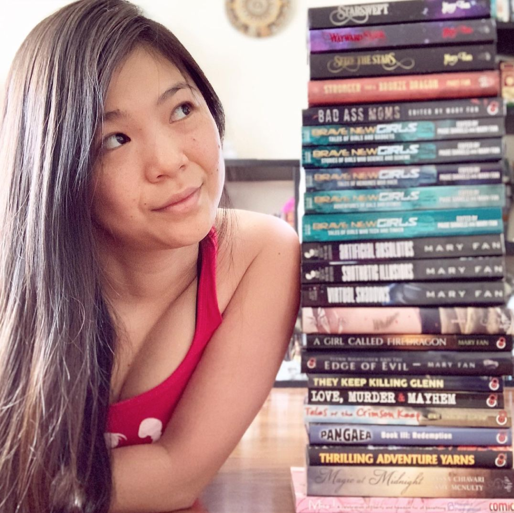Author Mary Fan next to a stack of books.