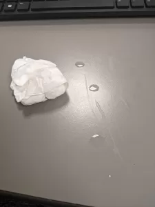 Tiny puddles of tears next to an used tissue on a gray desktop
